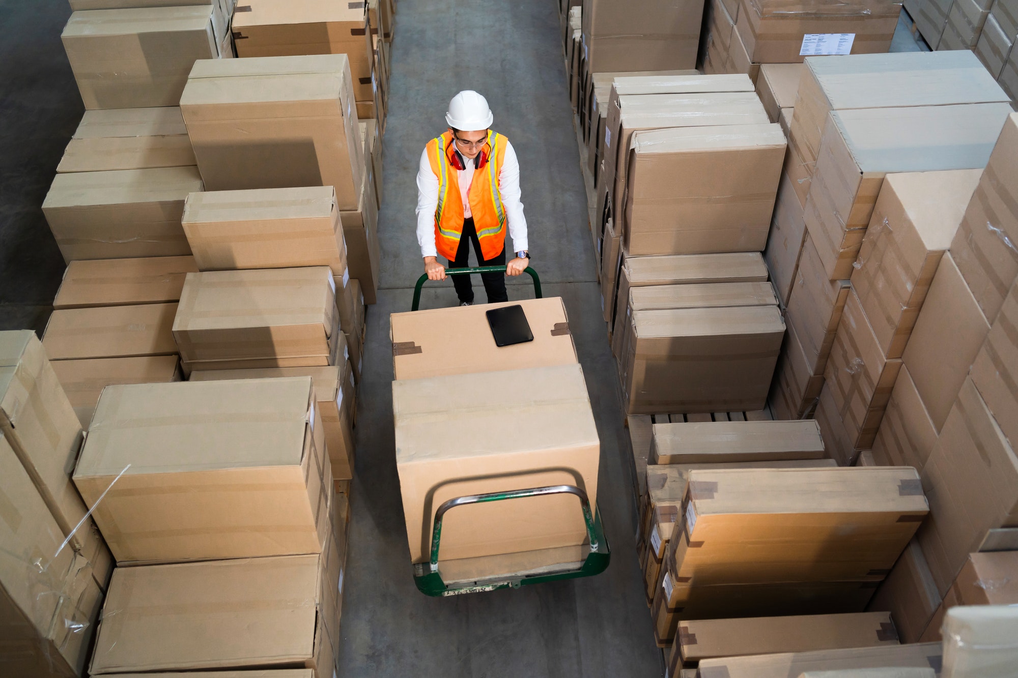 Logistic warehouse worker delivering boxes on a trolley